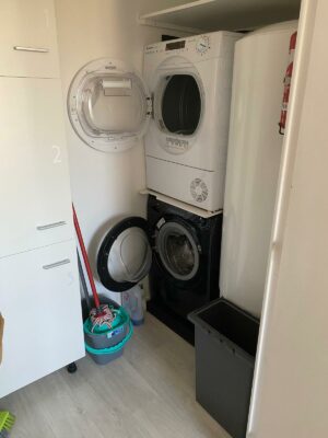 Espace buanderie optimisé avec machine à laver et sèche-linge superposés.