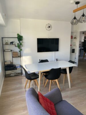 Salon moderne avec parquet clair, canapé gris anthracite et table à manger blanche épurée.